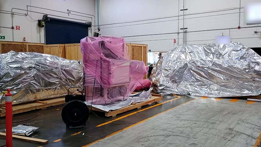 Máquinas sobre bases de madera, unas selladas en bolsa barrera de aluminio y otras envueltas en película estirable antiestática rosa, antes de cerrar las cajas